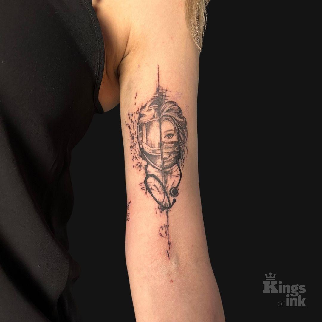 Twarz podzielona na pół, na jednej połowie ma na sobie kask, na drugiej maseczkę, szyję oplata stetoskop.