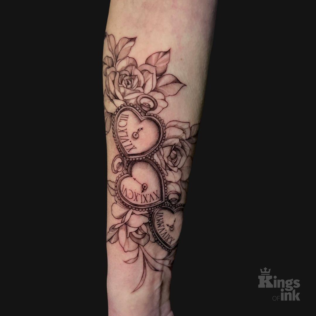 Trzy zegary z datą w kształcie serca, które oplatają kwiaty róży.