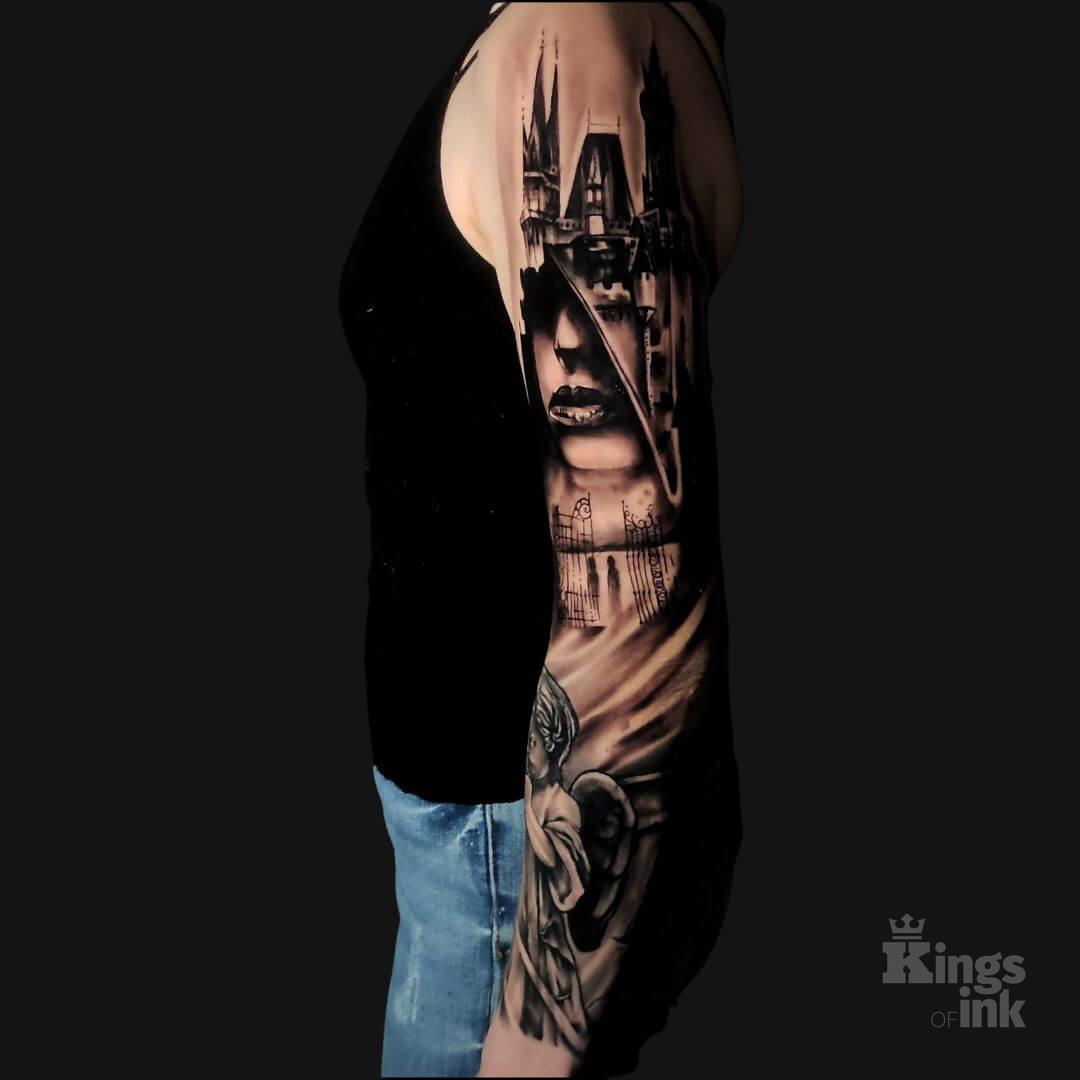 Anioł, nad którym znajduje się brama oraz budynek z twarzą kobiety.