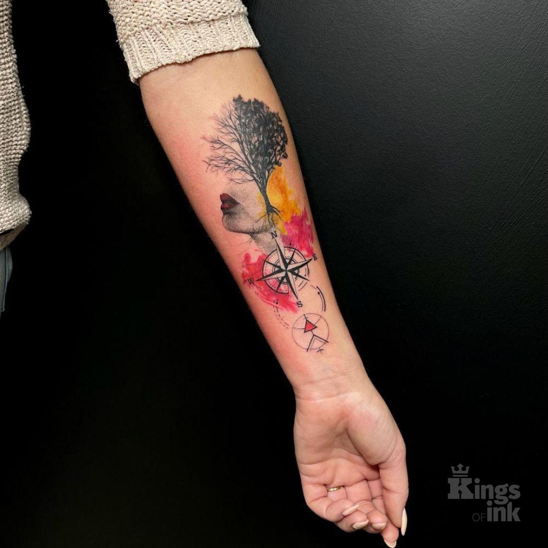 Kompas, nad którym znajduje się drzewo i twarz kobiety z czerwonymi ustami.