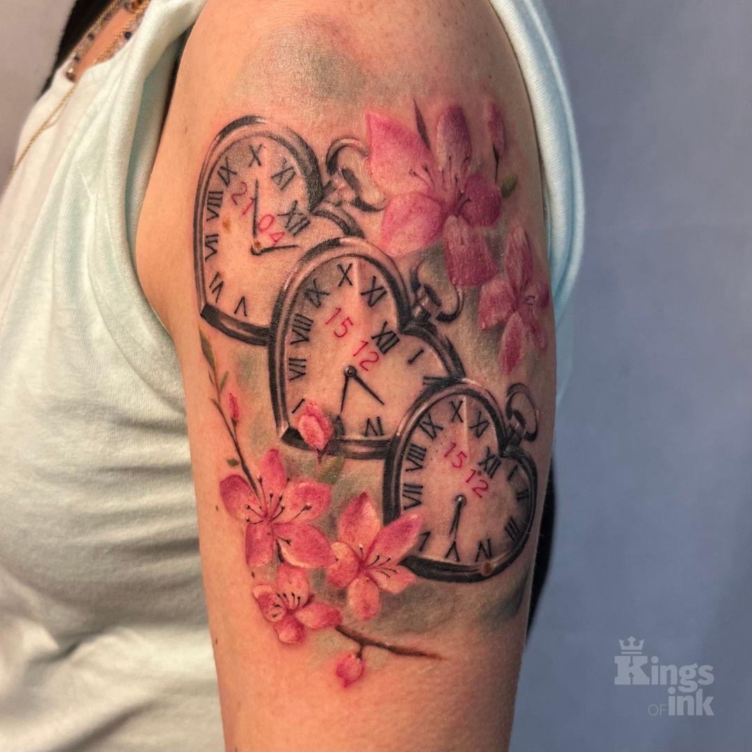 Zegary z datami w kształcie serca, wokół których są kwiaty.