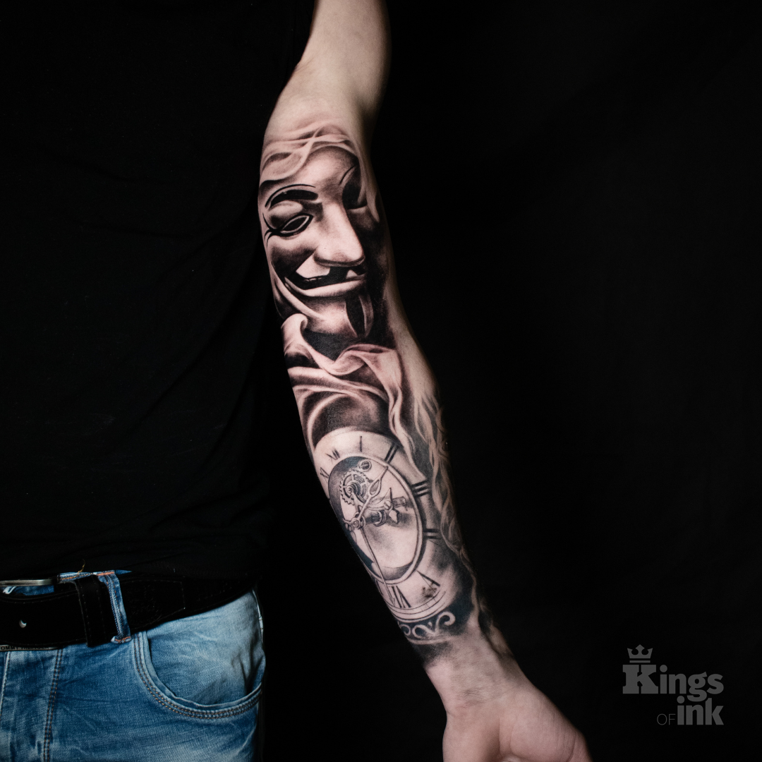 Maska mężczyzny, poniżej którego znajduje się zegar z kompasem.